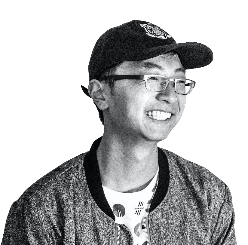 An Asian man in a cap and glasses grinning.